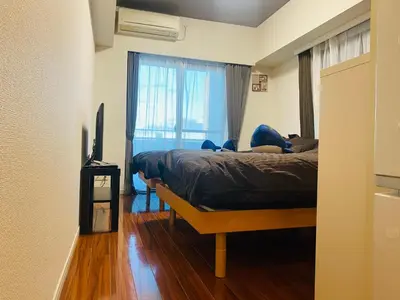 a bedroom with a bed and a television and a window at Shinjuku House in Tokyo