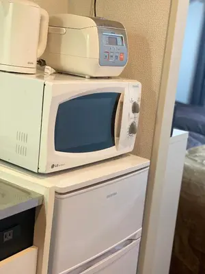 a microwave sitting on top of a refrigerator at Shinjuku House in Tokyo