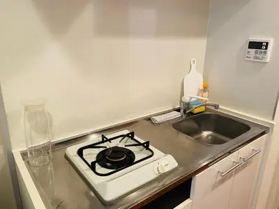 a kitchen counter with a stove and a sink at Shinjuku House in Tokyo