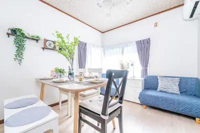 a dining room with a table and a blue couch at TK House Tokyo Ikebukuro Max5PPL in Tokyo