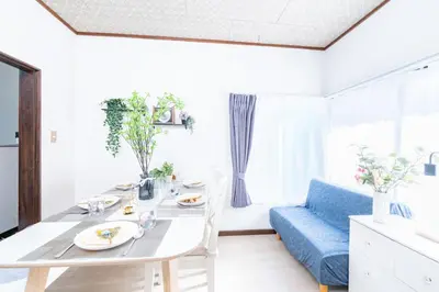 a white living room with a table and a blue couch at TK House Tokyo Ikebukuro Max5PPL in Tokyo