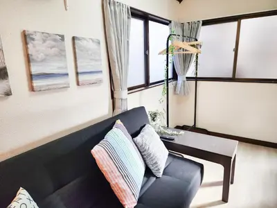a living room with a black couch and a table at TK House Tokyo Ikebukuro Max5PPL in Tokyo