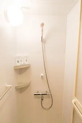 a shower in a bathroom with a light on the wall at Urayasu Villa in Tokyo