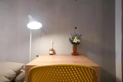 a table with a yellow chair and a vase of flowers at Fullea Yotsuya in Tokyo
