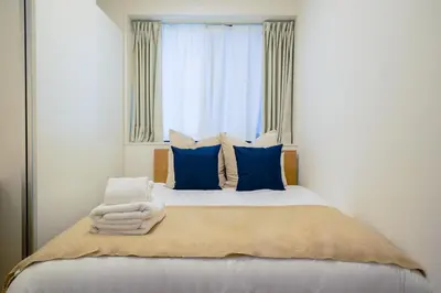 a bedroom with a bed with blue pillows and a window at Fullea Yotsuya in Tokyo