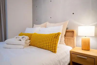 a bed with a yellow pillow and towels on it at Fullea Yotsuya in Tokyo
