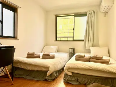 two beds in a small room with a window at Fuji Flat \u65b0\u5927\u4e45\u4fdd\u99c5\u304b\u3089\u5f92\u6b6920\u79d2 \u65b0\u5bbf\u99c5\u3082\u5f92\u6b6915\u5206 \u6709\u540d\u30ec\u30b9\u30c8\u30e9\u30f3\u591a\u6570 \u6b4c\u821e\u4f0e\u753a\u3082\u6b69\u3044\u3066\u884c\u3051\u307e\u3059 in Tokyo