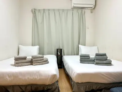 two beds with towels stacked on them in a room at Fuji Flat \u65b0\u5927\u4e45\u4fdd\u99c5\u304b\u3089\u5f92\u6b6920\u79d2 \u65b0\u5bbf\u99c5\u3082\u5f92\u6b6915\u5206 \u6709\u540d\u30ec\u30b9\u30c8\u30e9\u30f3\u591a\u6570 \u6b4c\u821e\u4f0e\u753a\u3082\u6b69\u3044\u3066\u884c\u3051\u307e\u3059 in Tokyo