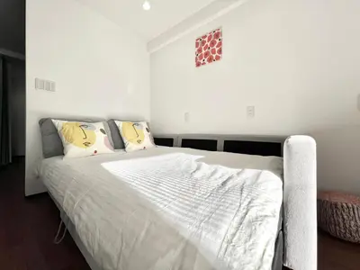 a bedroom with a bed with white sheets and pillows at KKHouse in Tokyo
