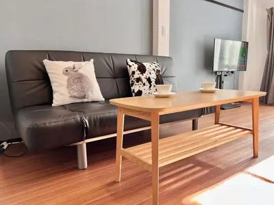 a living room with a leather couch and a wooden table at KKHouse in Tokyo