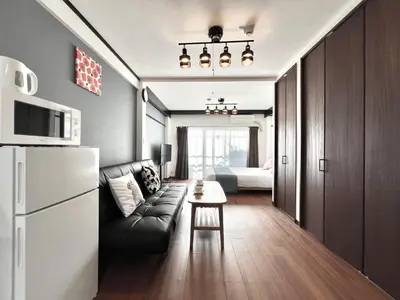 a living room with a couch and a table and a refrigerator at KKHouse in Tokyo