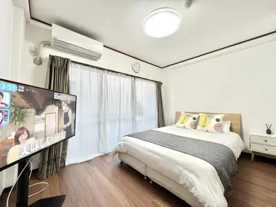 a bedroom with a bed and a flat screen tv at KKHouse in Tokyo