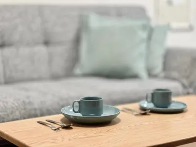 two coffee cups on a wooden table with a couch at KKHouse in Tokyo