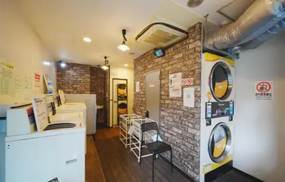a laundry room with a washer and a brick wall at \u6771\u4eac\u30ea\u30ea\u30a2\u30eb\u30db\u30c6\u30eb601 in Tokyo