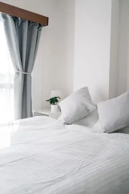 a bed with white sheets and pillows next to a window at \u590f\u7f8e\u30db\u30c6\u30eb in Tokyo