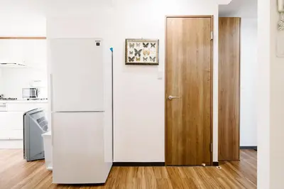 a white refrigerator and a wooden door in a kitchen at \u590f\u7f8e\u30db\u30c6\u30eb in Tokyo