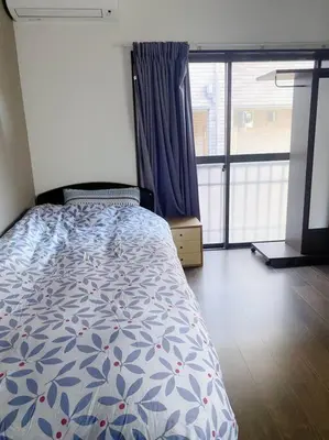 a bedroom with a bed and a large window at \u5c0f\u5ca9\u6c11\u6cca\u5bbf in Tokyo