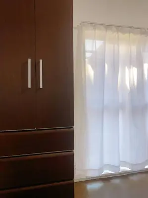 a window with a white curtain next to a dresser at \u5c0f\u5ca9\u6c11\u6cca\u5bbf in Tokyo