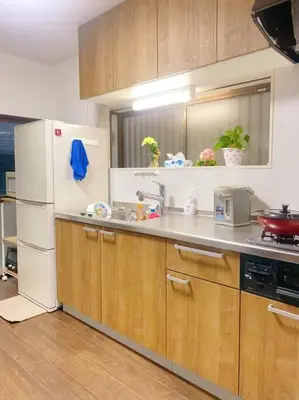 a kitchen with a white refrigerator and wooden cabinets at \u5c0f\u5ca9\u6c11\u6cca\u5bbf in Tokyo