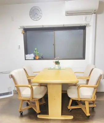 a table and chairs in a room with a clock at \u5c0f\u5ca9\u6c11\u6cca\u5bbf in Tokyo