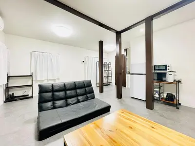 a living room with a black leather couch and a table at Alo BnB 10 - Near AKIHABARA, UENO, ASAKUSA, TOKYO SKY TREE - Self check-in in Tokyo
