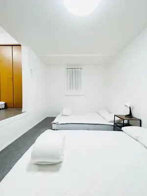 a white bedroom with two beds and a table at Alo BnB 10 - Near AKIHABARA, UENO, ASAKUSA, TOKYO SKY TREE - Self check-in in Tokyo
