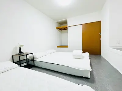 a white bedroom with two beds and a wooden door at Alo BnB 10 - Near AKIHABARA, UENO, ASAKUSA, TOKYO SKY TREE - Self check-in in Tokyo