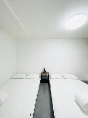 two beds in a room with a white wall at Alo BnB 10 - Near AKIHABARA, UENO, ASAKUSA, TOKYO SKY TREE - Self check-in in Tokyo