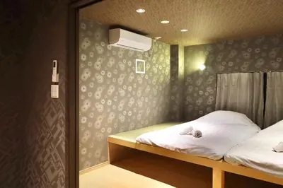a room with two beds and a wall with wallpaper at \u6cca\u9732Hakuro 1\u968e in Tokyo