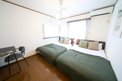 a bedroom with two beds and a desk with a desk at FINOA Residential Suite Kita-Ikebukuro in Tokyo