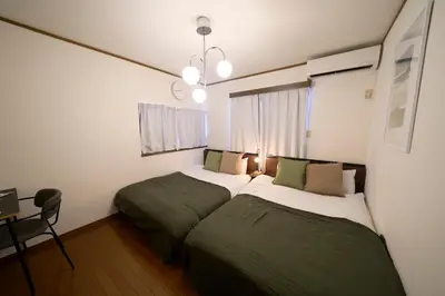 a bedroom with two beds and a table and a chandelier at FINOA Residential Suite Kita-Ikebukuro in Tokyo
