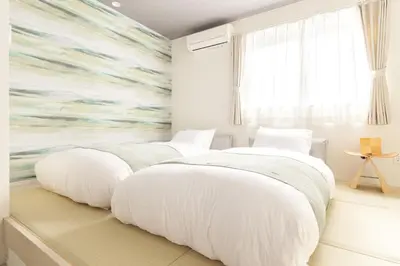two beds in a bedroom with a mural at Home Suite Home Ikejiri - Shibuya 1 Stop! Sleek Confort with Washer and Dryer in Tokyo