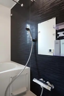 a shower head in a bathroom with a black wall at Home Suite Home Ikejiri - Shibuya 1 Stop! Sleek Confort with Washer and Dryer in Tokyo