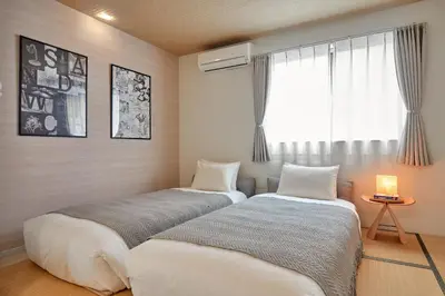 two beds in a room with a window at Home Suite Home Ikejiri - Shibuya 1 Stop! Sleek Confort with Washer and Dryer in Tokyo