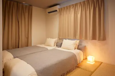 two beds sitting in a room with a window at Home Suite Home Ikejiri - Shibuya 1 Stop! Sleek Confort with Washer and Dryer in Tokyo
