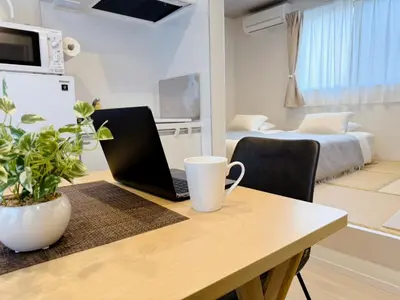 a laptop computer sitting on a wooden table in a room at Home Suite Home Ikejiri - Shibuya 1 Stop! Sleek Confort with Washer and Dryer in Tokyo