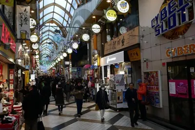 a group of people walking through a shopping mall at \u677e\u304c\u4e181\u4e01\u76ee in Tokyo