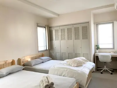 a bedroom with two beds and a desk and two windows at MIKO'S HOUSE SETAGAYA, Peaceful Tokyo Home Near Shinjuku, Experience Authentic Local Living, Lucky Cat Temple, Super Market 東京の家 新宿10分 隠れ家カフェ 豪徳寺 in Tokyo