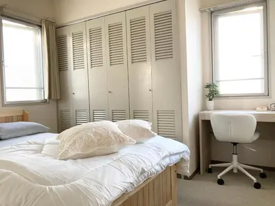 a bedroom with a bed and a desk and two windows at MIKO'S HOUSE SETAGAYA, Peaceful Tokyo Home Near Shinjuku, Experience Authentic Local Living, Lucky Cat Temple, Super Market 東京の家 新宿10分 隠れ家カフェ 豪徳寺 in Tokyo