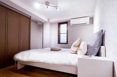 a bedroom with a bed with white sheets and pillows at Charming Guesthouse in the Heart of Okubo \u4e36Steps to Metro and Convenient Travel! EoW4 in Tokyo