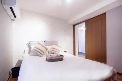 a bedroom with a large white bed with a wooden door at Charming Guesthouse in the Heart of Okubo \u4e36Steps to Metro and Convenient Travel! EoW4 in Tokyo