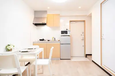 a kitchen with a table and a white refrigerator at CG Charming Guesthouse in the Heart of Okubo \u4e36Steps to Metro and Convenient Travel! YoE4 in Tokyo