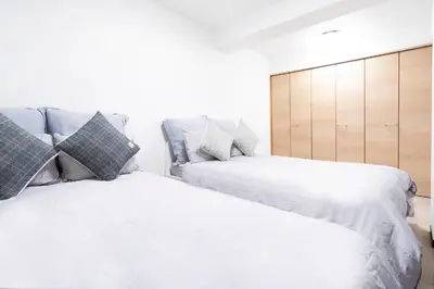 two beds with white sheets and pillows in a bedroom at CG Charming Guesthouse in the Heart of Okubo \u4e36Steps to Metro and Convenient Travel! YoE4 in Tokyo