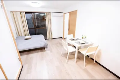 a small room with a bed and a table and chairs at CG Charming Guesthouse in the Heart of Okubo \u4e36Steps to Metro and Convenient Travel! YoE4 in Tokyo