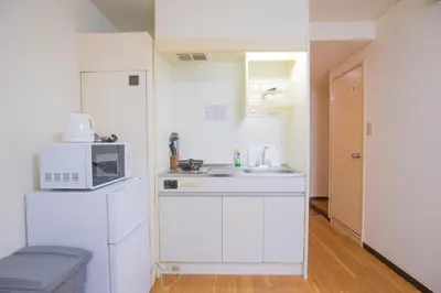 a small white kitchen with a microwave and a sink at Charming Guesthouse in the Heart of Okubo \u4e36Steps to Metro and Convenient Travel! EoS11 in Tokyo