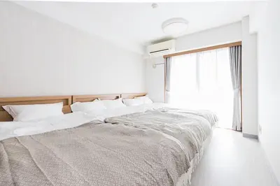 a white bedroom with a large bed with a window at 2 Minutes Walk to Ikebukuro Station, Central Tokyo and Very Convenient in Tokyo