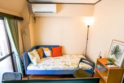a small room with a bed with colorful pillows at Near Shinjyuku hostel in Tokyo
