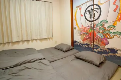 two beds in a room with a painting on the wall at 2\u968e \u5c0f\u5ca9\u99c5\u5f92\u6b6915\u5206 \u53ce\u5bb94\u4eba \u6210\u7530\u7fbd\u7530\u304b\u3089\u30d0\u30b9\u76f4\u901a in Tokyo