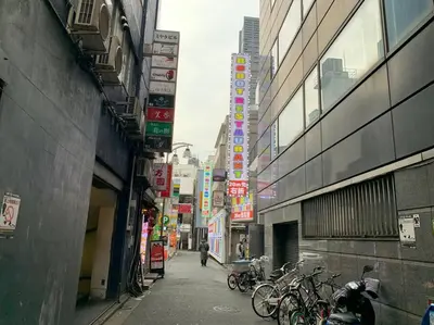 a city alley with bikes parked on the sides of buildings at \u672c\u753a2\u4e01\u76ee in Tokyo