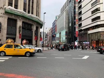 a yellow taxi cab driving down a busy city street at \u672c\u753a2\u4e01\u76ee in Tokyo